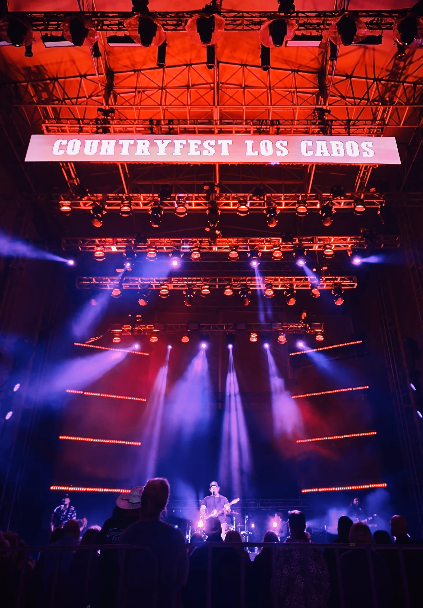 Escenario de Country Fest Los Cabos con pantalla LED roja y haces de luz sobre el público