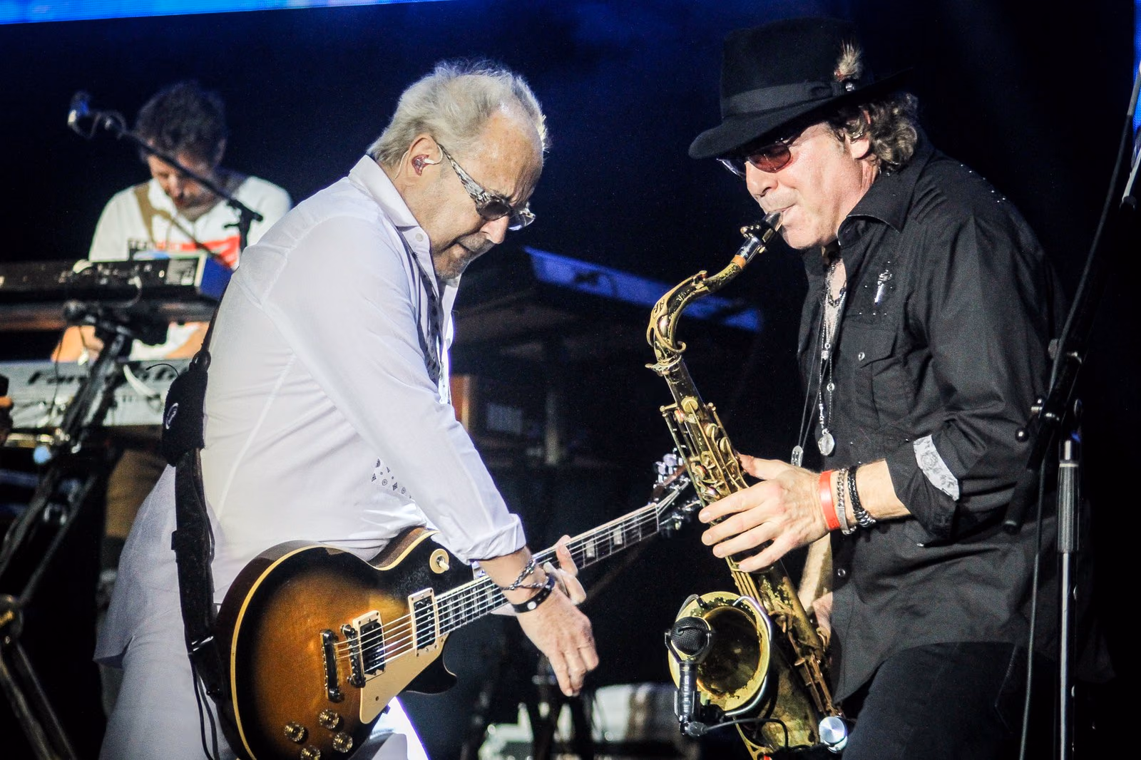 Músicos de Foreigner tocando guitarra y saxofón en el escenario